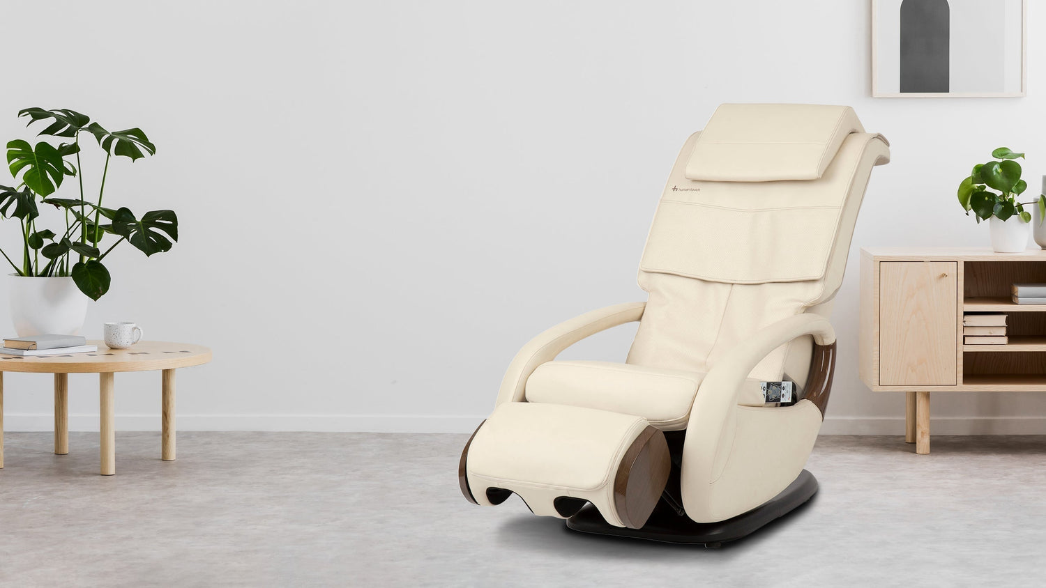 Cream compact massage chair with brown base in a bright minimalist room with monstera plants and wooden furniture