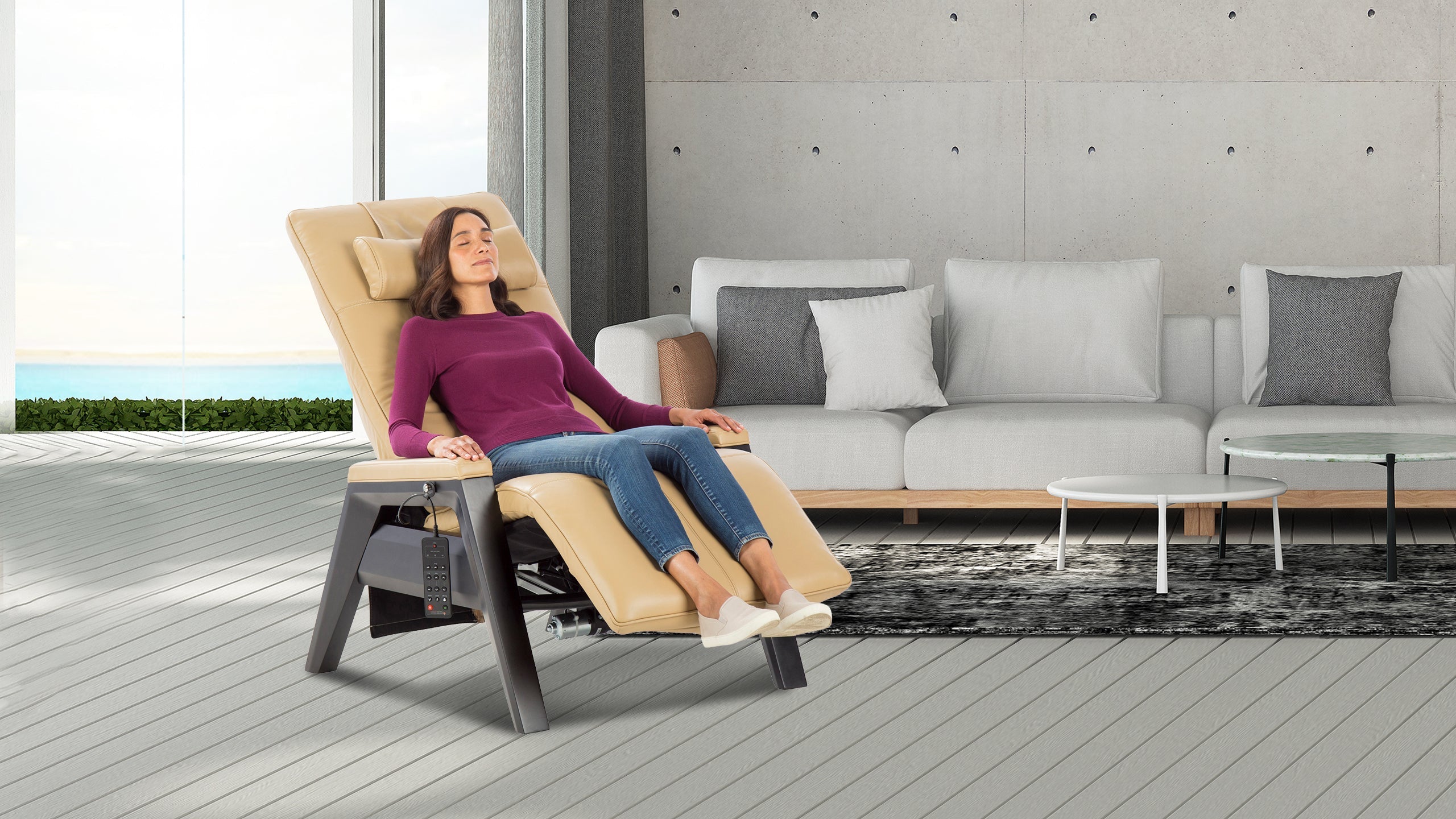 Woman relaxing with eyes closed in a beige zero gravity chair with gray frame in a contemporary living room with ocean view