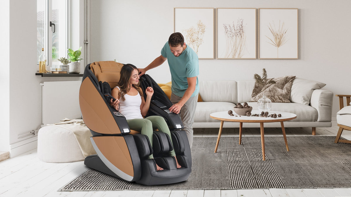 Smiling man standing beside a woman sitting in a tan and black massage chair in a bright Scandinavian living room