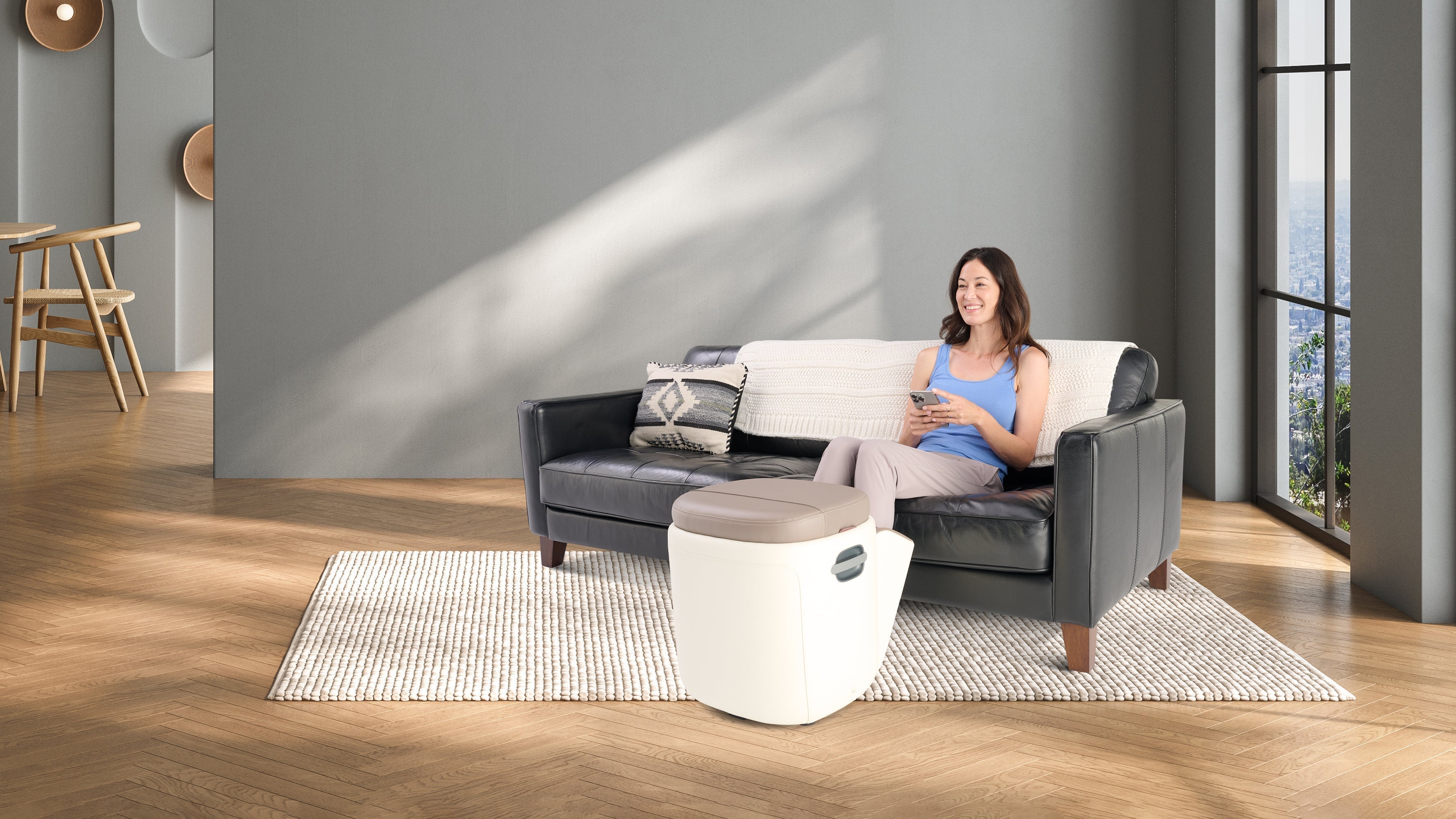 Woman relaxing on sofa using smartphone to control a foot massager machine in a modern living room