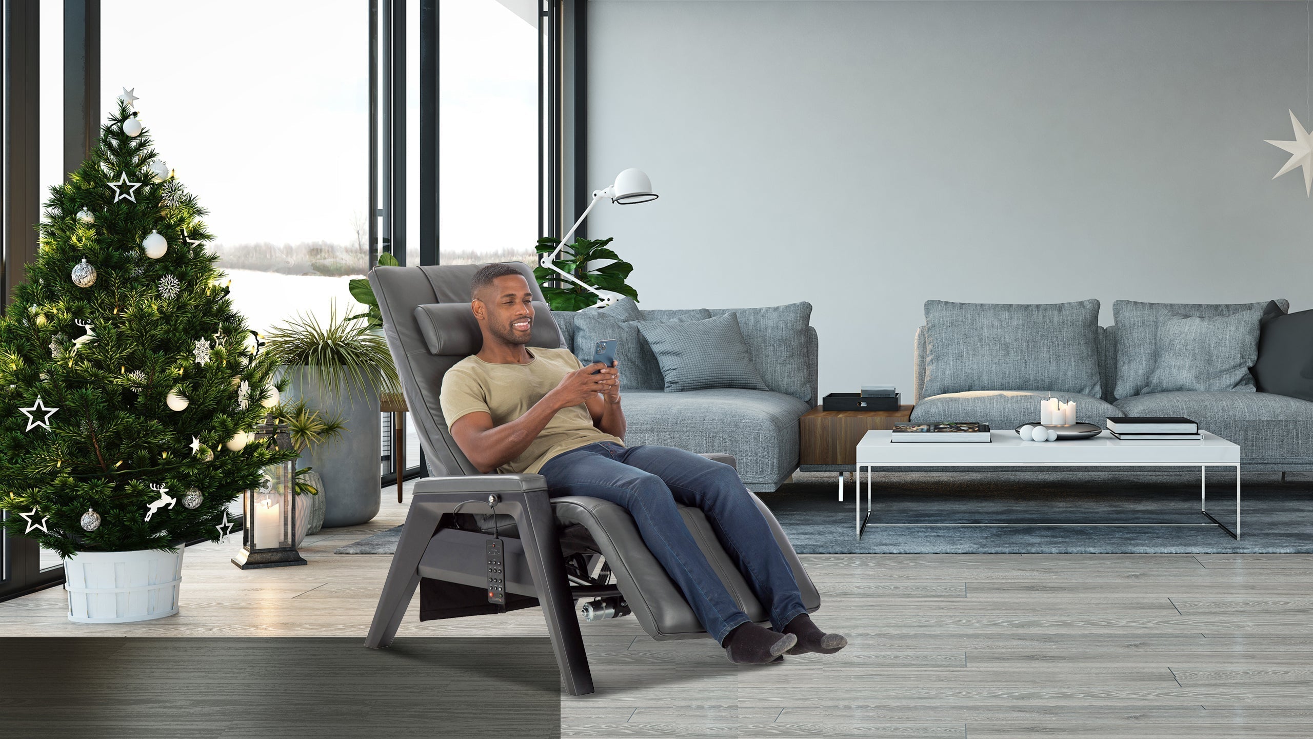 Man smiling at his phone in a gray zero gravity chair next to a decorated Christmas tree in a modern living room