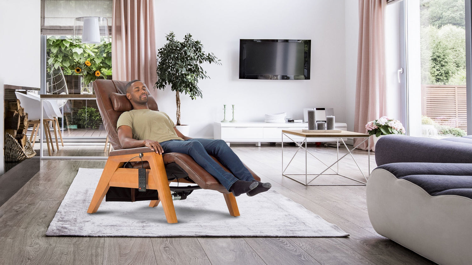 Man relaxing with eyes closed in a brown leather zero gravity chair with light wooden legs in a bright modern living room