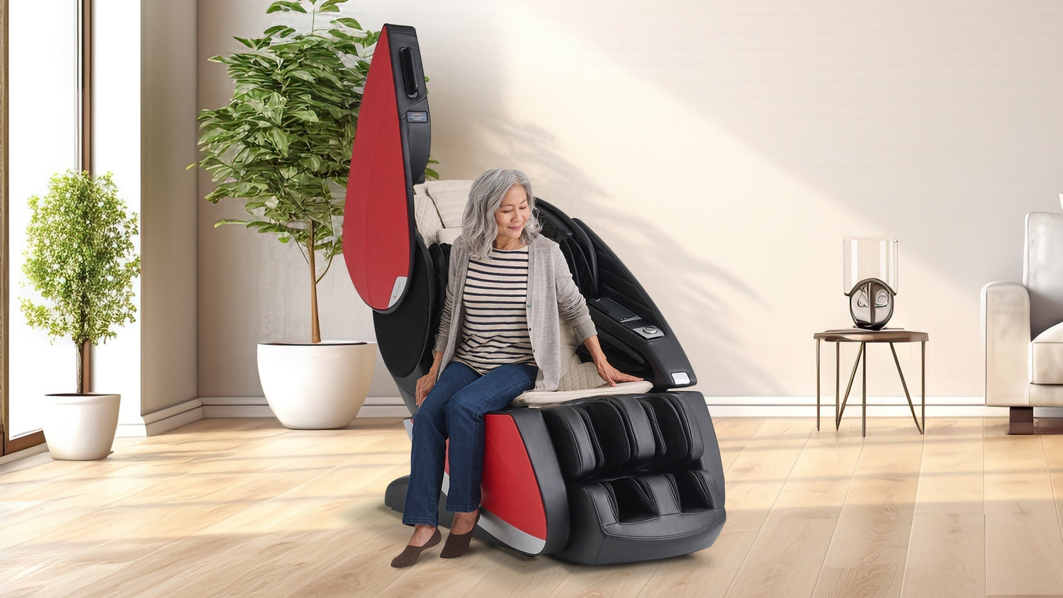 Older woman with gray hair sitting in a black and red massage chair with open side panel in a bright living room