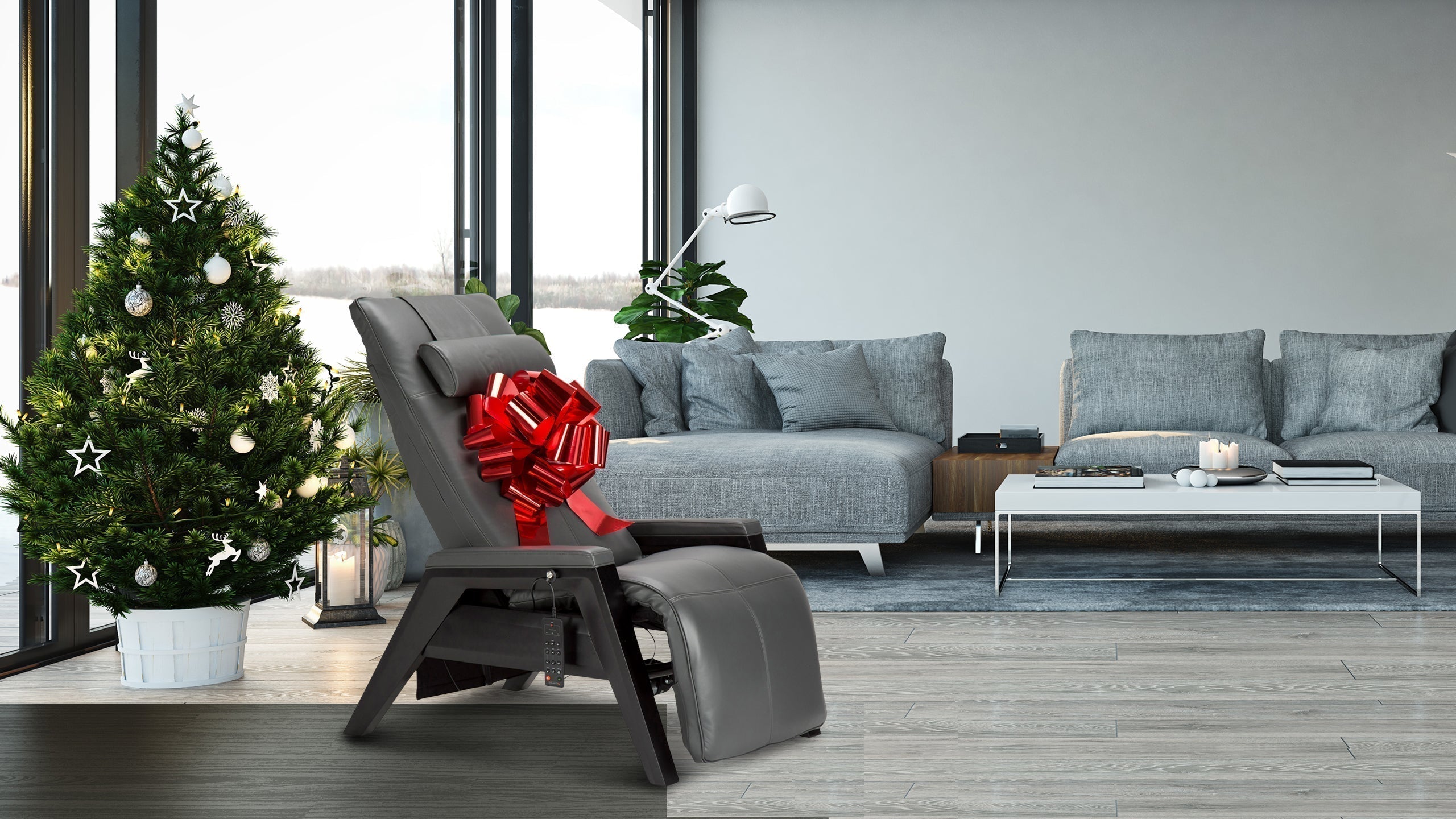 Gray leather zero gravity chair with a red gift bow next to a decorated Christmas tree in a modern living room