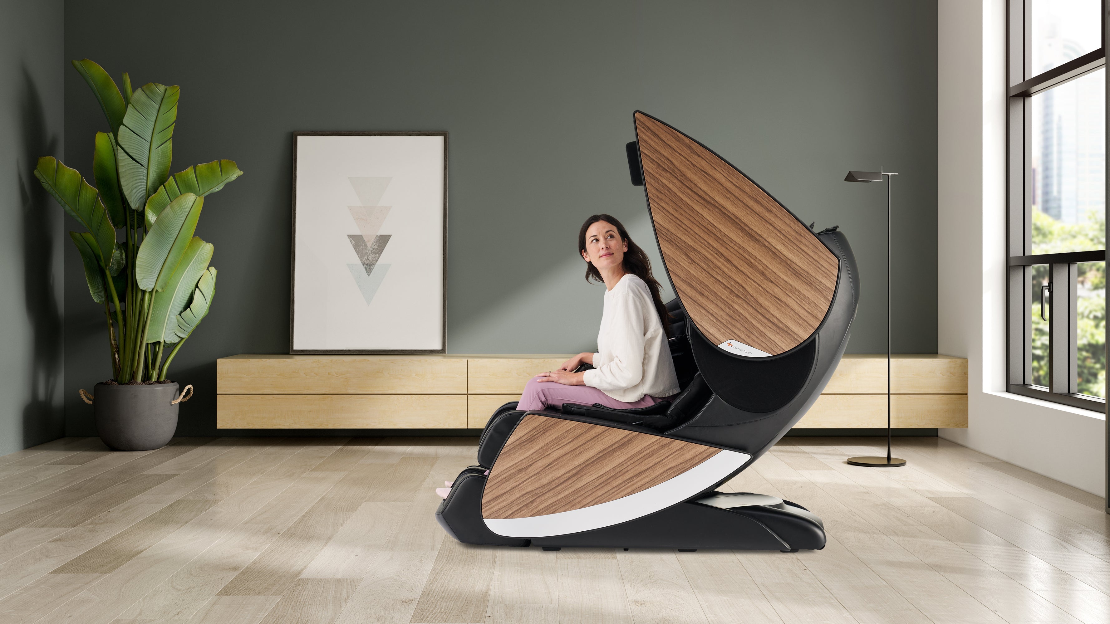 Woman sitting in luxury massage chair with walnut wood panel design in modern Scandinavian living room