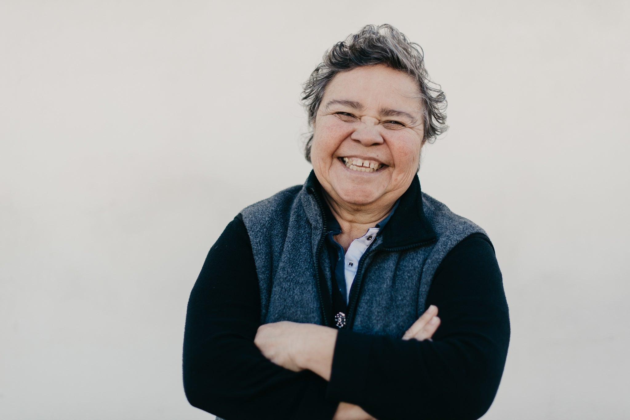 Woman leaning against a wall laughing.