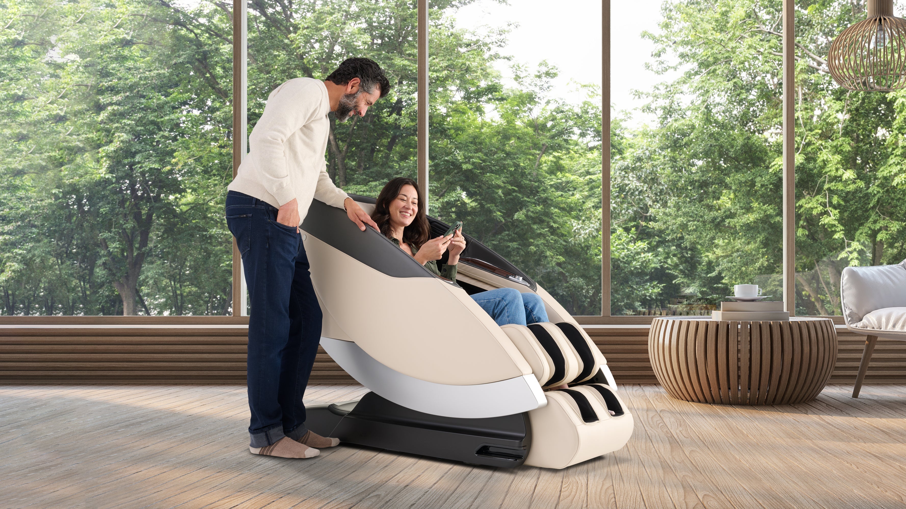 Woman relaxing in cream full body massage chair while man assists with remote control in luxury living room