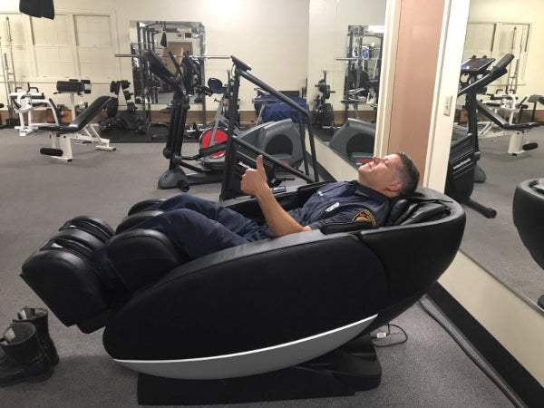 LA Firefighter using a Human Touch massage chair in a gym setting