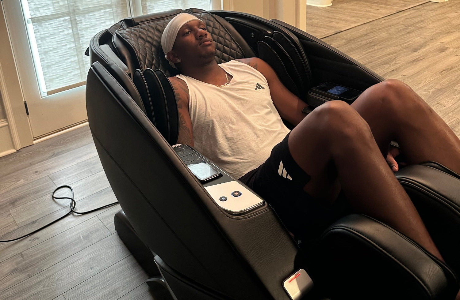 Michael Penix JR using a massage chair in a home setting.