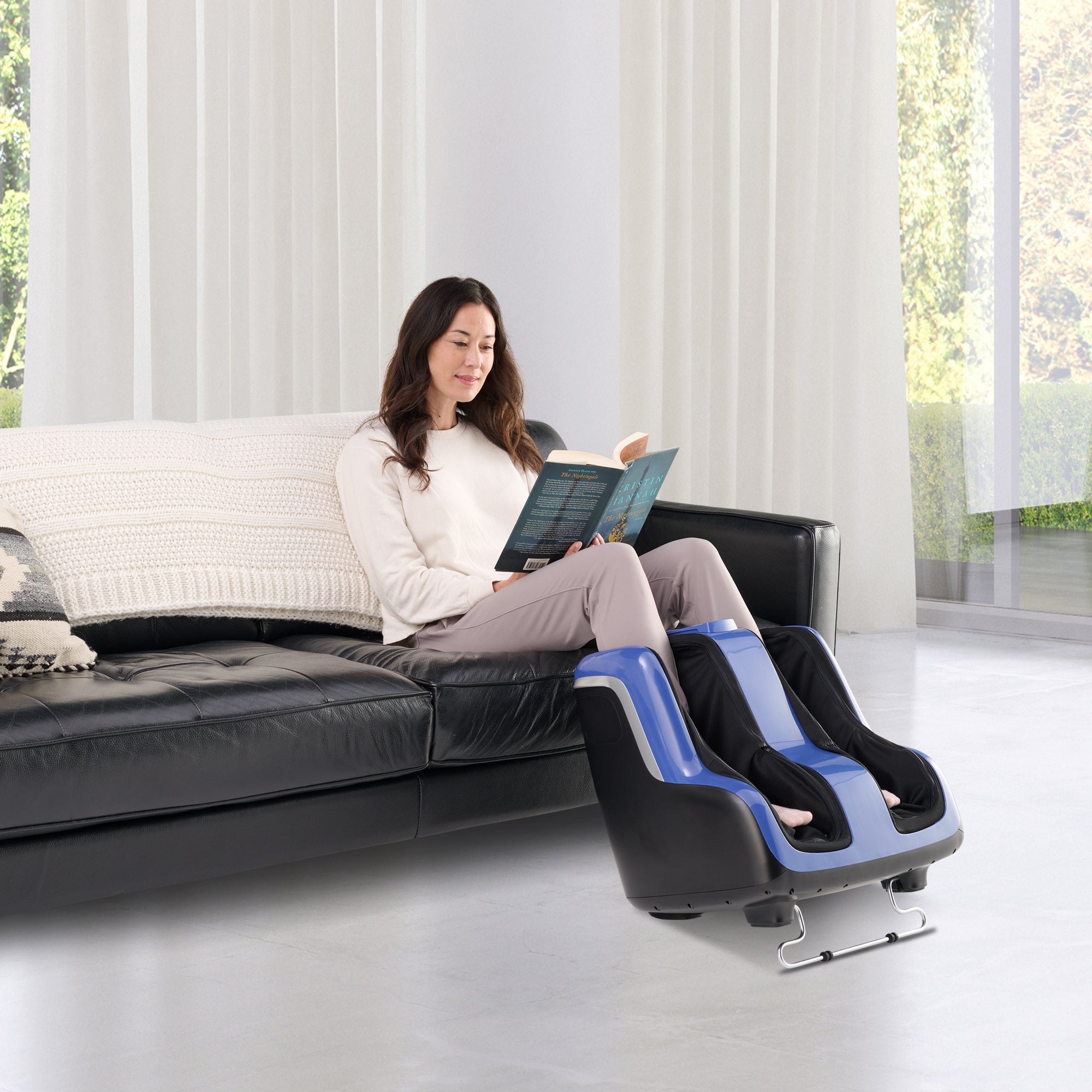 Reflex SOL Plus foot massager with heat therapy shown in modern living room with person relaxing on black leather couch