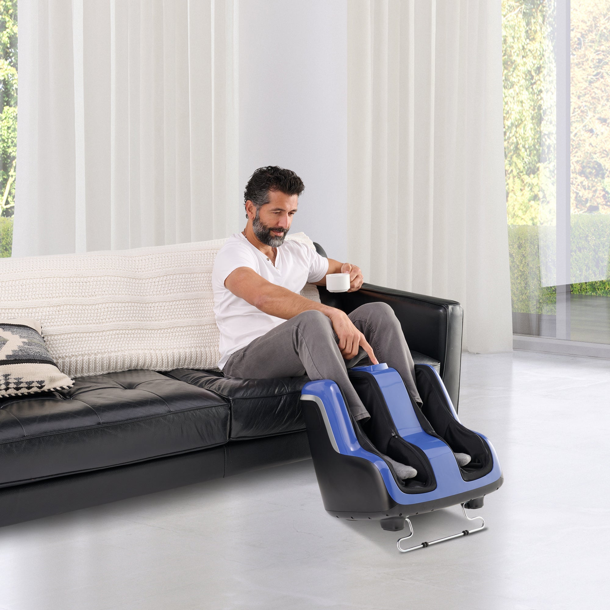 Reflex SOL Plus Foot and Calf Massager shown in use on couch, featuring black and blue design for home relaxation