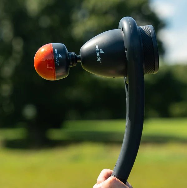 Handheld massage device with a blurred green outdoor background