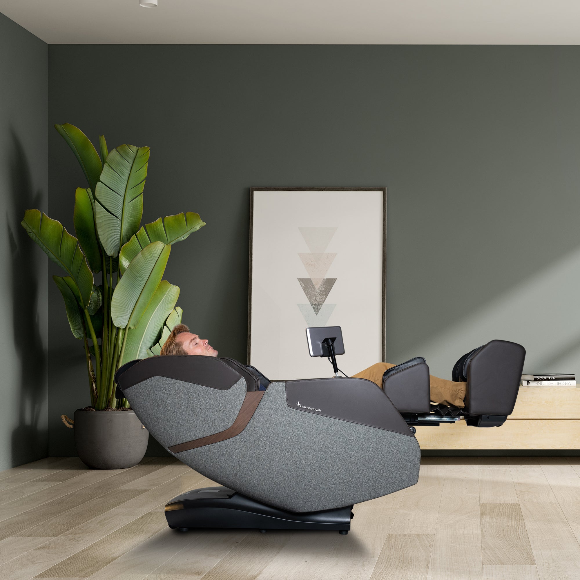 WholeBody ROVE massage chair in grey shown in modern room with green walls and potted plant, demonstrating recline feature