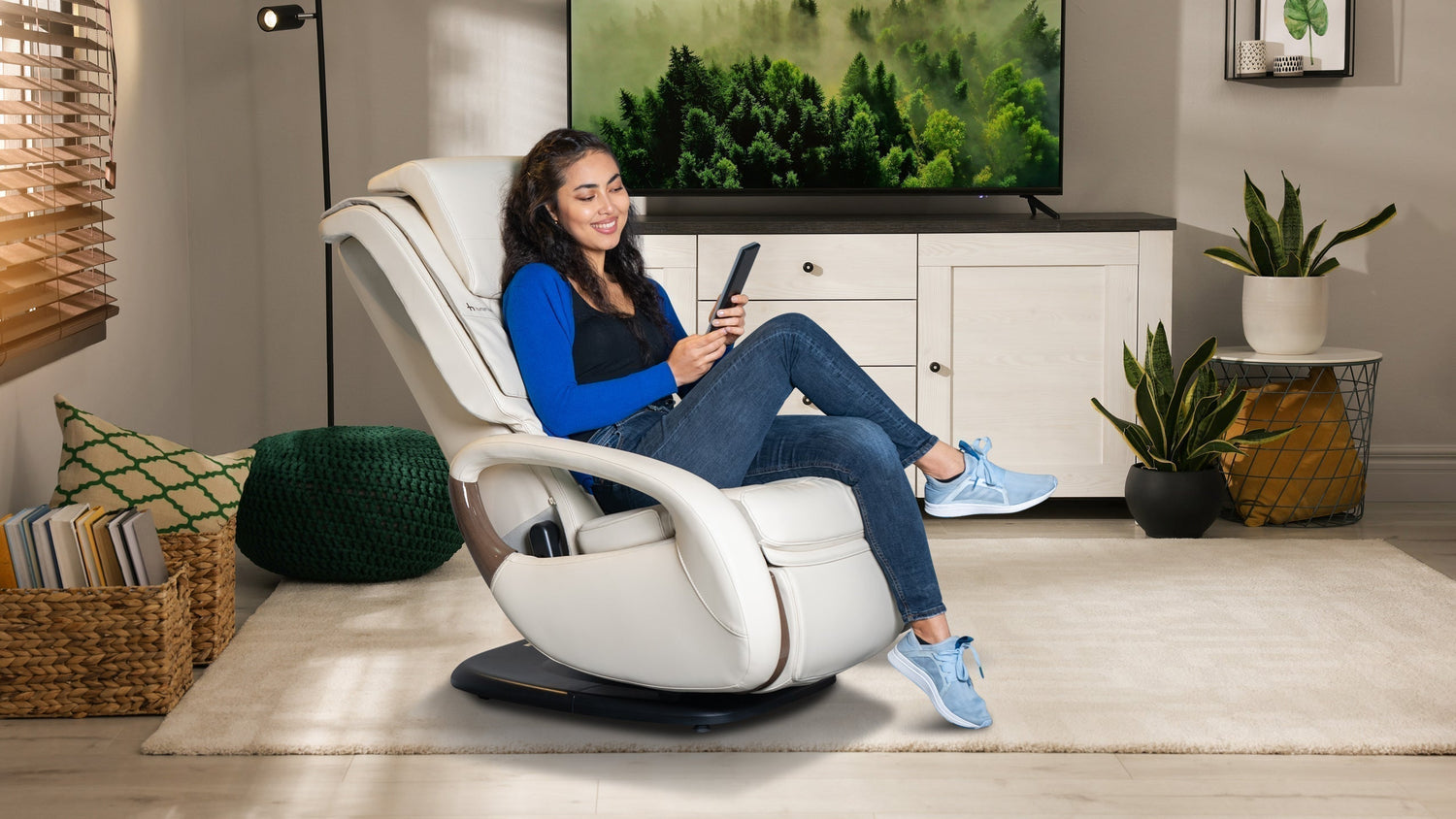 Young woman using remote control while sitting in white leather massage recliner chair in cozy living room