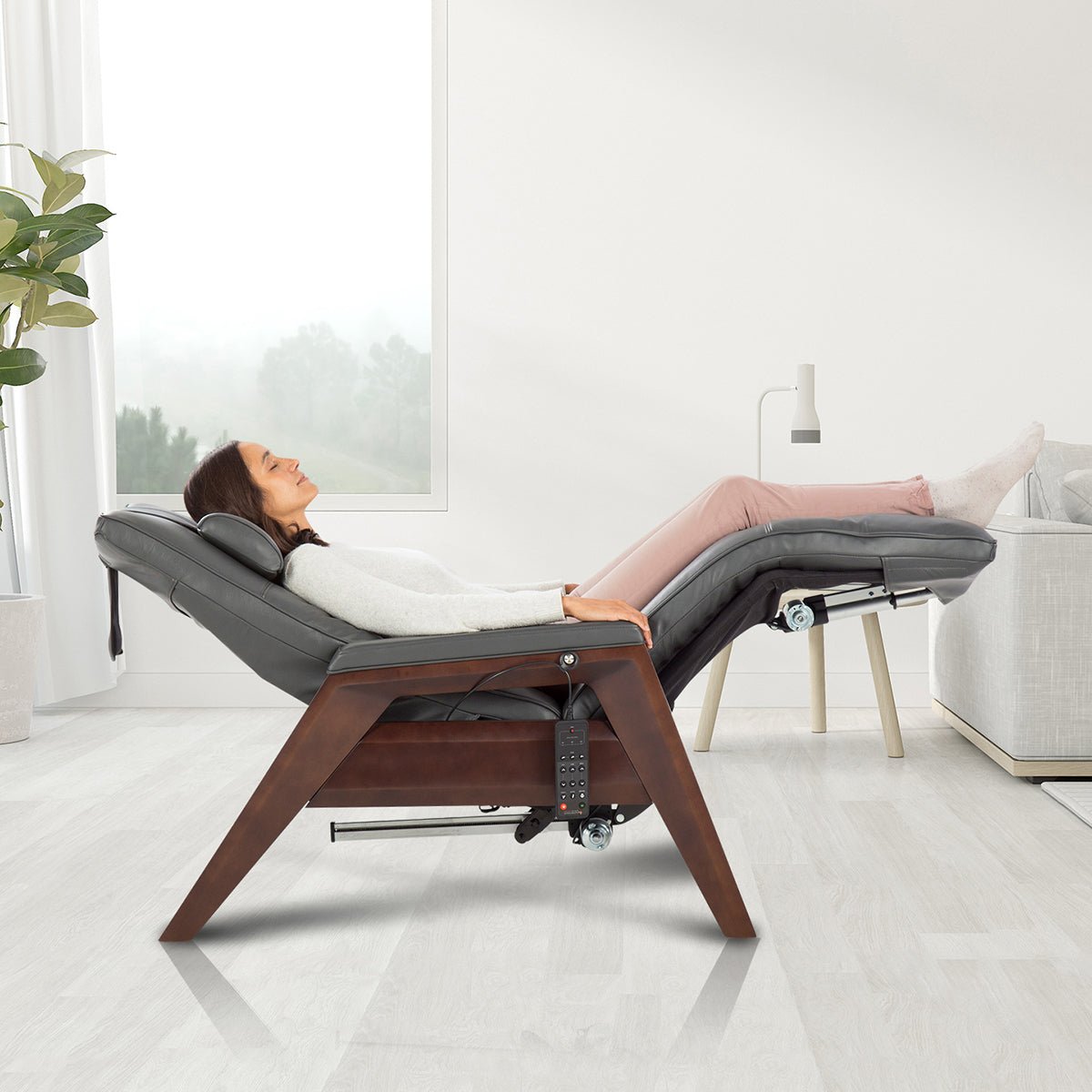 Gravis ZG Chair in zero gravity position with person relaxing in modern living room setting near window and plant