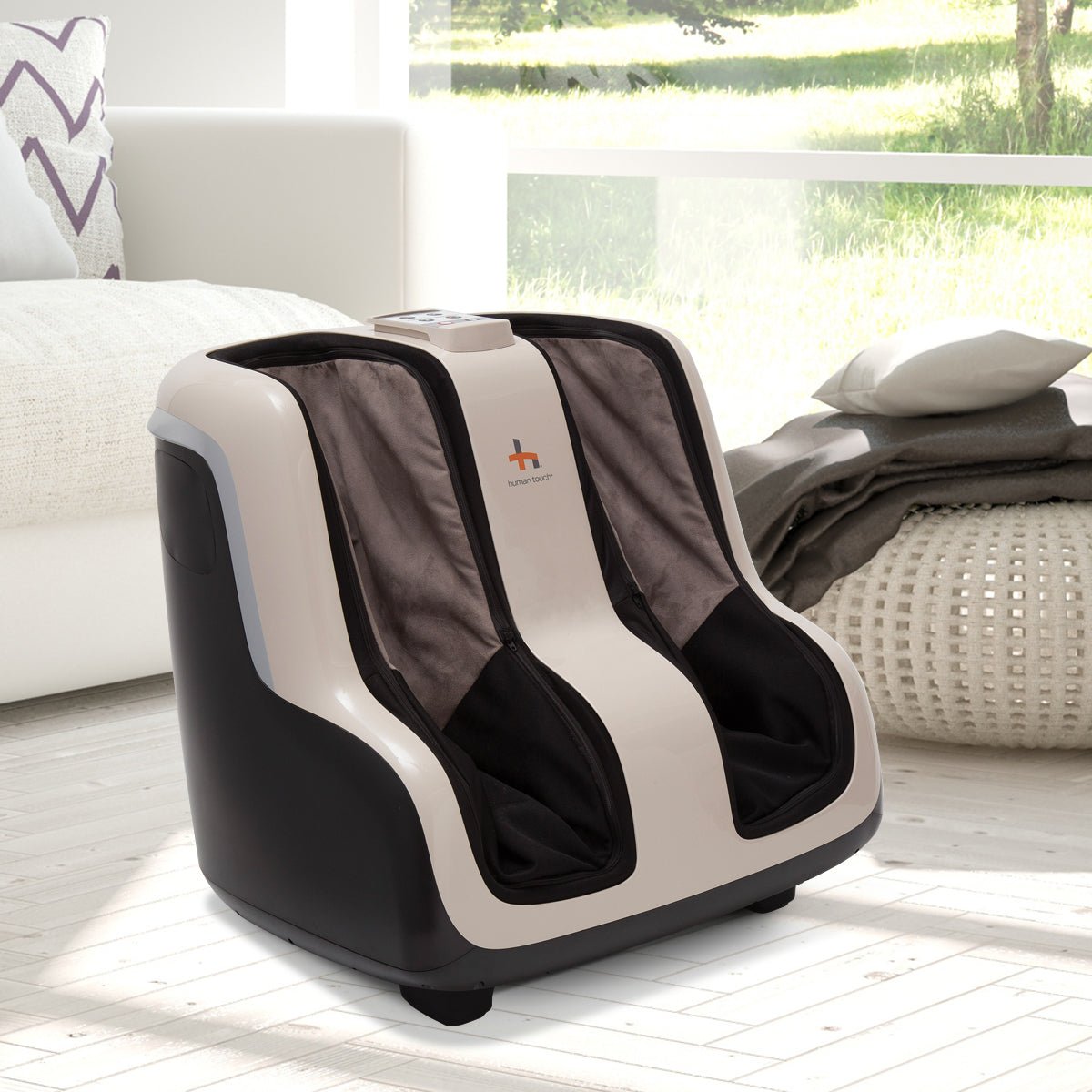 Reflex SOL Foot and Calf Massager shown in white and black design on living room floor beside white couch