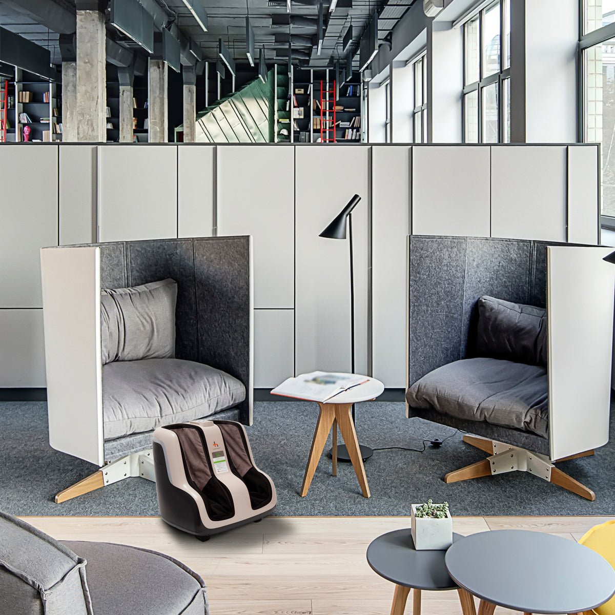 Reflex SOL Foot and Calf Massager displayed in modern office lounge between two private seating pods with gray cushions