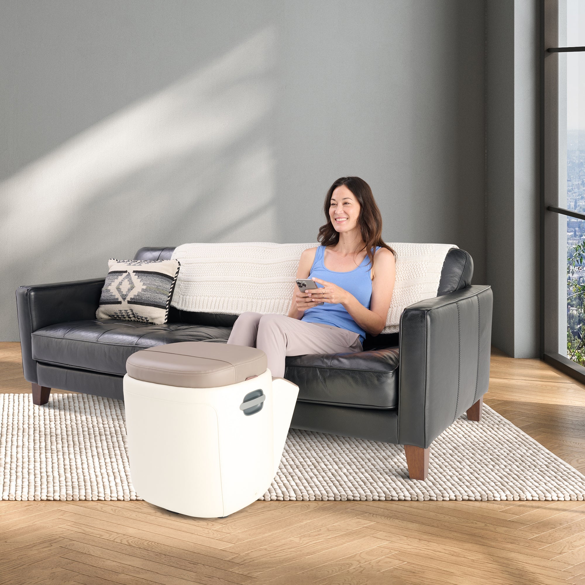 Person relaxing on couch using Reveal Ottoman Massager for foot therapy in modern living room setting