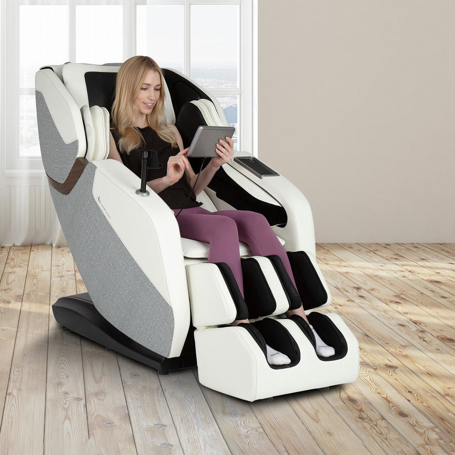 WholeBody ROVE massage chair in white and gray shown in modern room with person relaxing while using tablet