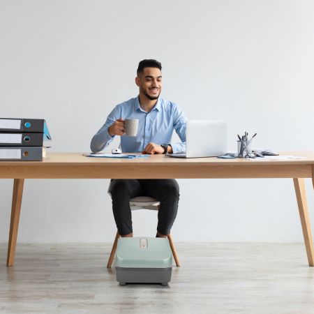 Man using the Reflex PopUp Foot massager at his office desk